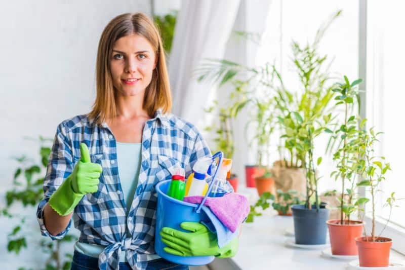 benefits of green cleaning, girl handling a cleaning solutions with plants beside her.