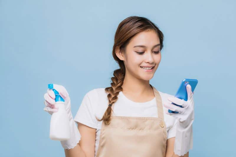 a women holding a spray bottle and a phone