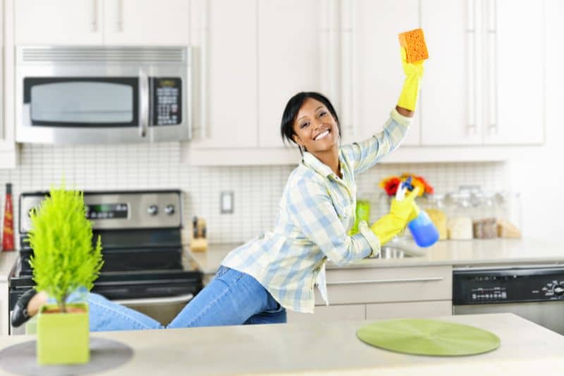 a women whose happy DIY cleaning the kitchen with holding a sponge and spray bottle