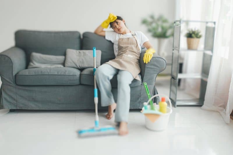 a women sitting in the coach with cleaning supplies