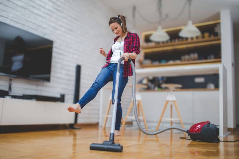 a women whos wearing a headset while DIY cleaning the floor and 
holding a vacuum